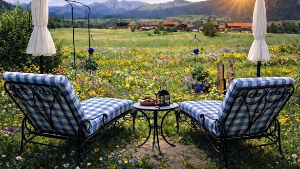 Un jardín con dos sillones a cuadros, una mesa y sombrillas.