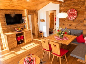 A cozy wooden interior with a dining area, a television, and a clock on the wall.
