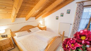 A wooden bed with a headboard, a bedside table with a lamp, and a window with curtains. - Ferienwohnung Nr. 5, 48 qm, Nichtraucher, 1 Schlafzimmer, Wohnraum/Kochnische, Balkon, Sat-TV, 4 Sterne, max 3 Personen (Anger)
