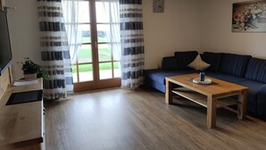 A living room with a sofa, a wooden coffee table, and a television on a stand.