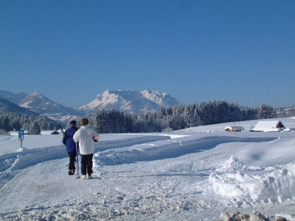 A snowy landscape with a clear sky and mountains in the background.