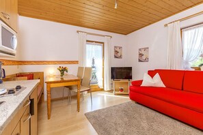 A compact living space with a dining area, a red sofa, and a television.