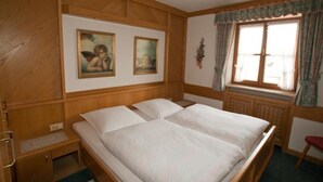 Un lit double avec une tête de lit en bois, une table de chevet et une fenêtre avec des rideaux.