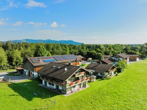 Un barrio residencial con varias casas, algunas con paneles solares, rodeado de campos verdes y árboles.