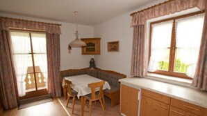Une pièce chaleureuse comprenant une table à manger, des chaises, un canapé, un buffet et une fenêtre avec des rideaux.
