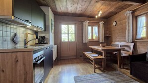 A cozy cabin-style kitchen with wooden cabinets, a dining table, and a sofa.