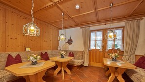 Et hyggeligt rum med trævægge og -loft, med en sofa, to træborde med blomsterarrangementer og hængende pendellamper.