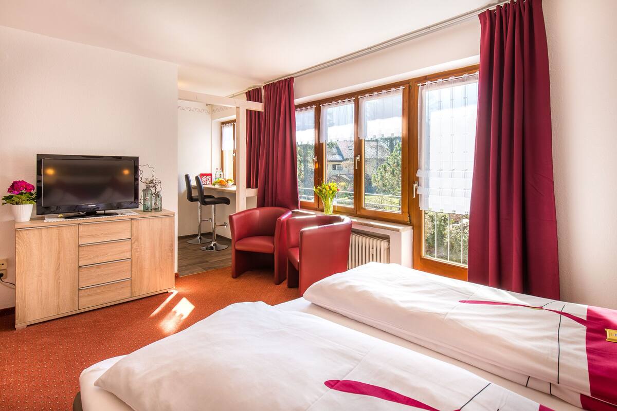 Een hotelkamer met een bed, een bureau met een televisie, een stoel en uitzicht op buiten.
