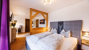 A bedroom with a large bed, a wooden headboard, a mirror, and a bedside table with a lamp. - Gästehaus Wolfgang (Ruhpolding)