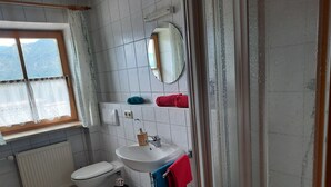 Un baño con inodoro, lavamanos, espejo y ventana con vistas a montañas.