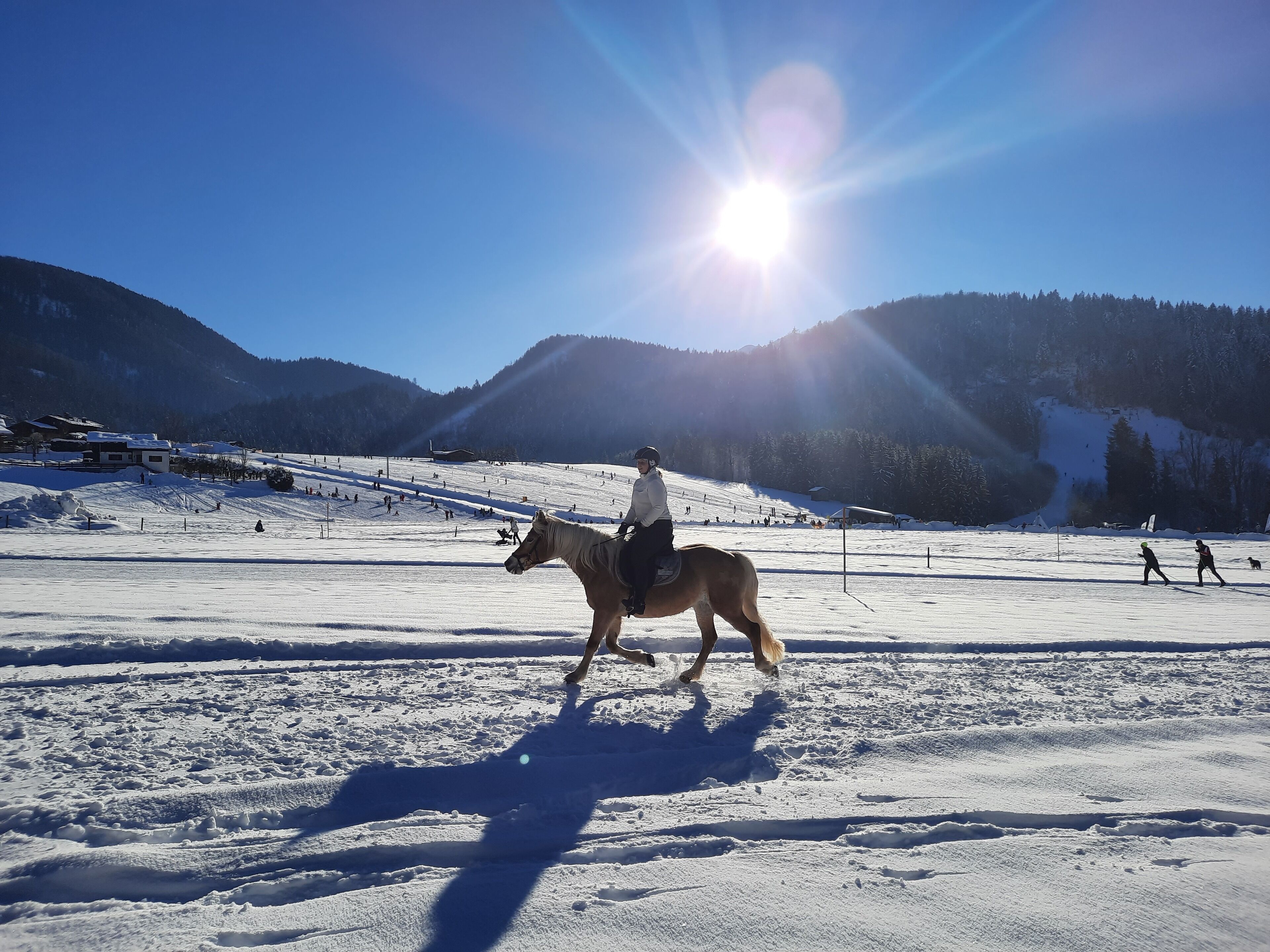 Pista de esquí nevada con una persona montando a caballo.