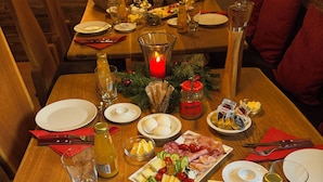 A dining table set with plates, cutlery, glasses, and a variety of food items including cheese, meats, and vegetables. - Alpenglühn (Berchtesgaden)