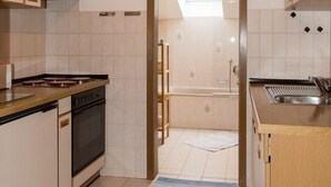 Moderni keittiö, jossa on puiset kaapit, sisäänrakennettu uuni ja kattovalokuvio.