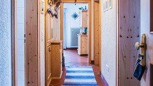 A hallway with wooden doors, a blue and white striped rug, and a ceiling light fixture.