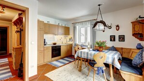 A cozy kitchen with wooden cabinets, a dining area with a checkered tablecloth, and a seating area with a sofa.