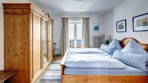 A bedroom with a wooden bed, a wardrobe, and a view of the outdoors through a door.