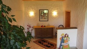 Una habitación con techo y mueble de madera, un cuadro enmarcado en la pared y un cartel de bienvenida.