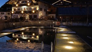 A building with a balcony, a pond, and a solar panel. - Ferienwohnung Erdgeschoß (Reit im Winkl)