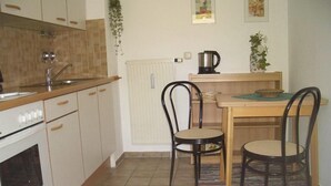Une petite cuisine équipée d’une cuisinière, d’un évier et d’une table à manger avec deux chaises.