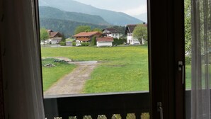 A room with a view of a rural landscape, including houses and a path. - (5) Zwei-Raum-Ferienwohnung 50qm, Bad/WC, Extra-Schlafraum, Küche, Balkon (Reit im Winkl)