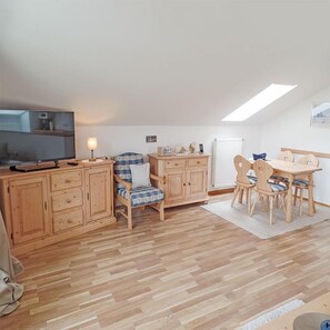 Une pièce chaleureuse avec un plancher en bois, une table à manger avec des chaises, un téléviseur et un meuble avec des tiroirs.