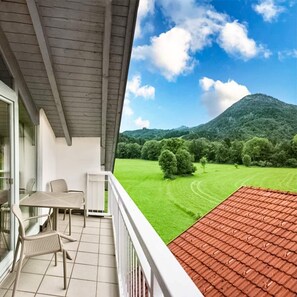 A balcony with a table and chairs, overlooking a green field and a mountain. - 1 1/2-room vacation apartment Kranzhorn, 40sqm, balcony (Oberaudorf)