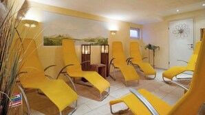 A room with yellow chairs arranged in a semi-circle, a door with a floral design, and a wall-mounted lamp.