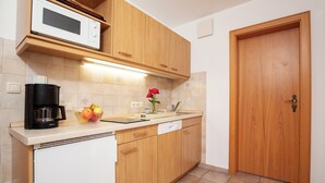 A kitchen with wooden cabinets, a microwave, a coffee maker, and a sink. - One-room apartment 30sqm, shower/WC, kitchen, balcony (Reit im Winkl)