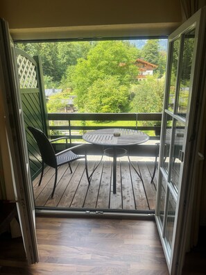 An open sliding glass door leading to an outdoor patio with a round table and two chairs.