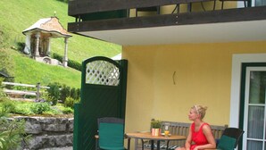 Un patio con mesa y sillas, un pequeño jardín y un edificio al fondo.
