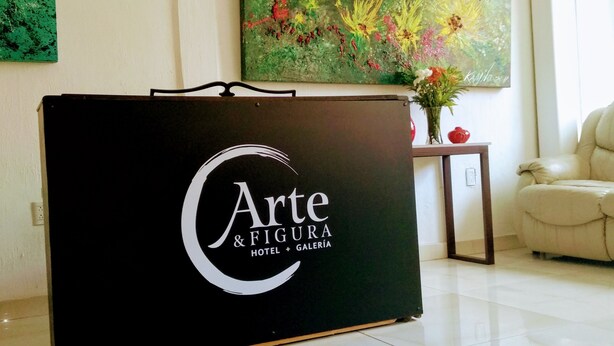 Un comptoir d’accueil orné du logo de l’hôtel « Arte & Figura Hotel + Galeria ».