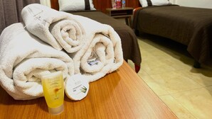 Une chambre d’hôtel avec deux lits, une tête de lit en bois et une table de chevet avec des articles de toilette.