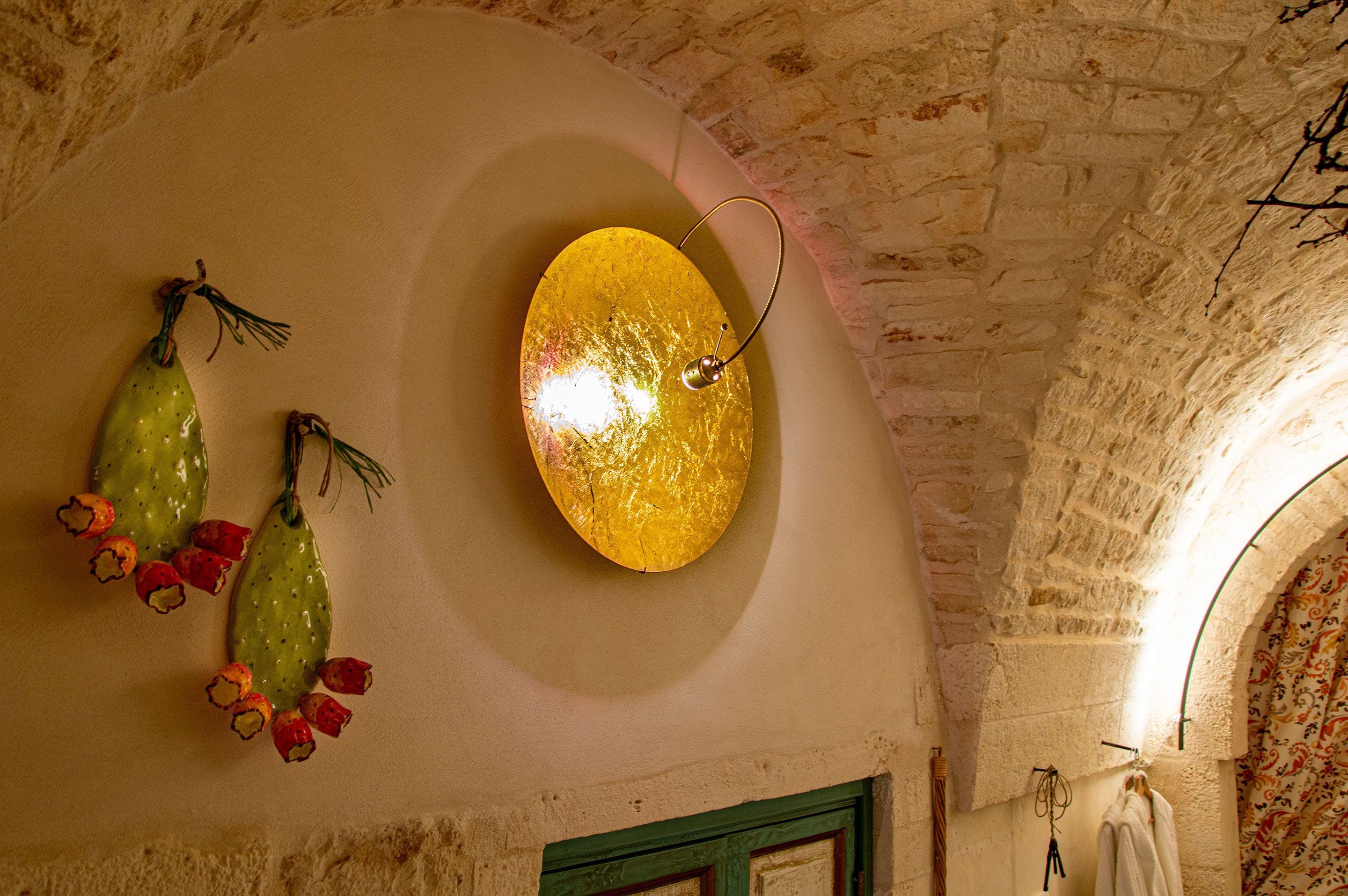 A room with a stone wall, a round light fixture, and decorative cactus-like objects.