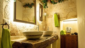 A rustic bathroom with a wooden countertop, two large bowls, a mirror, and a wooden cabinet. - Relais Santa Maria (Martina Franca)