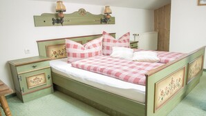 A bedroom with a green bed, checkered bedding, a nightstand, and a dresser. - Apartment 3, 25sqm, balcony, living/bedroom, kitchen, WLAN, FLat-TV (Ruhpolding)