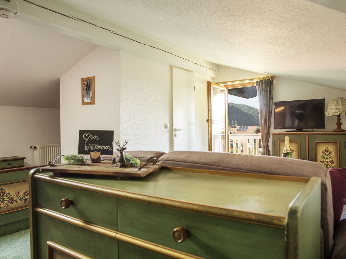 Ein Zimmer mit einem grünen Schminktisch, einem Fernseher und einem Schild mit der Aufschrift 'Willkommen'.