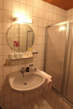 Bathroom features a round mirror, sink, and glass shower enclosure.