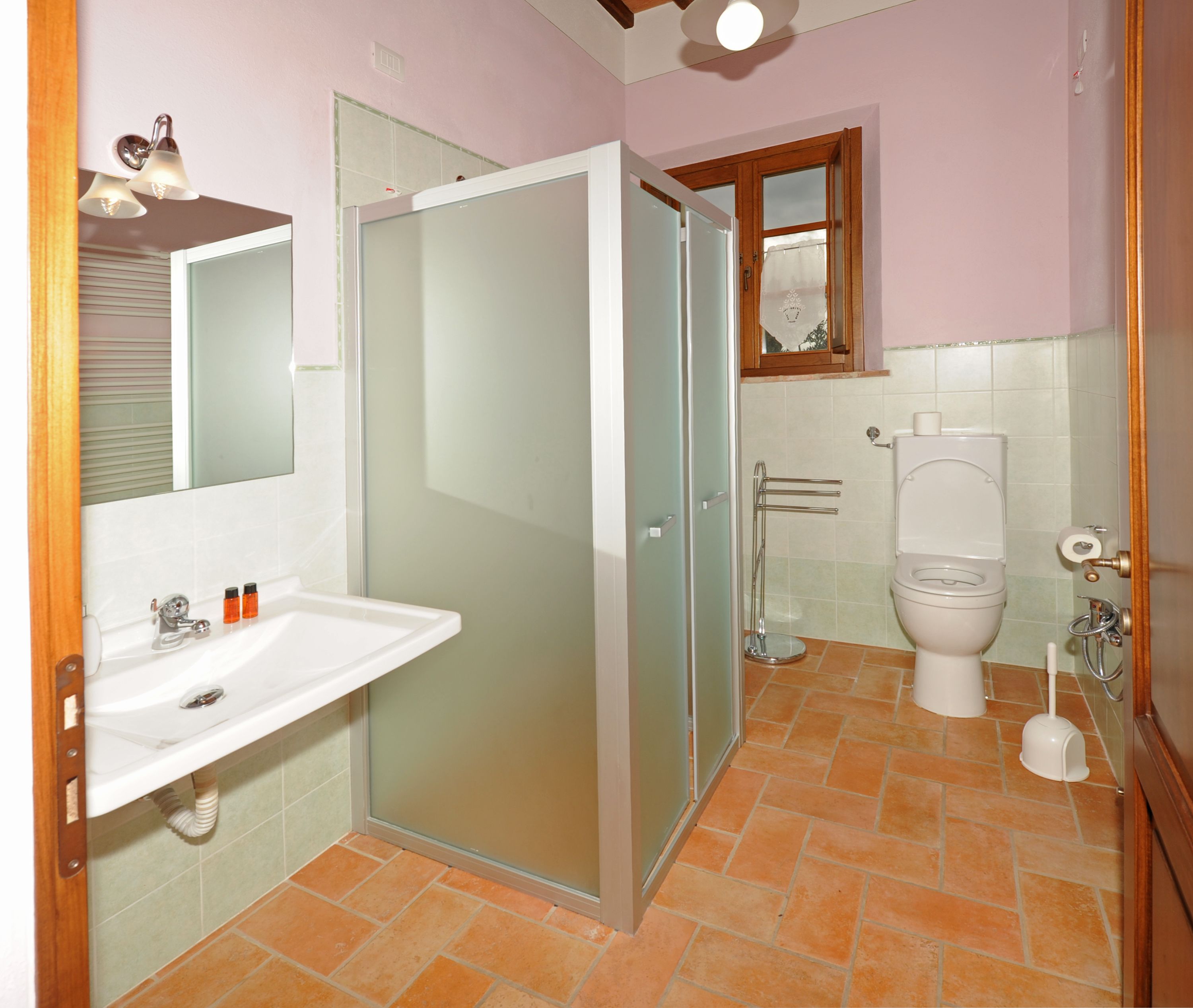 Une salle de bain avec une douche à parois de verre, un lavabo avec un miroir et des toilettes.