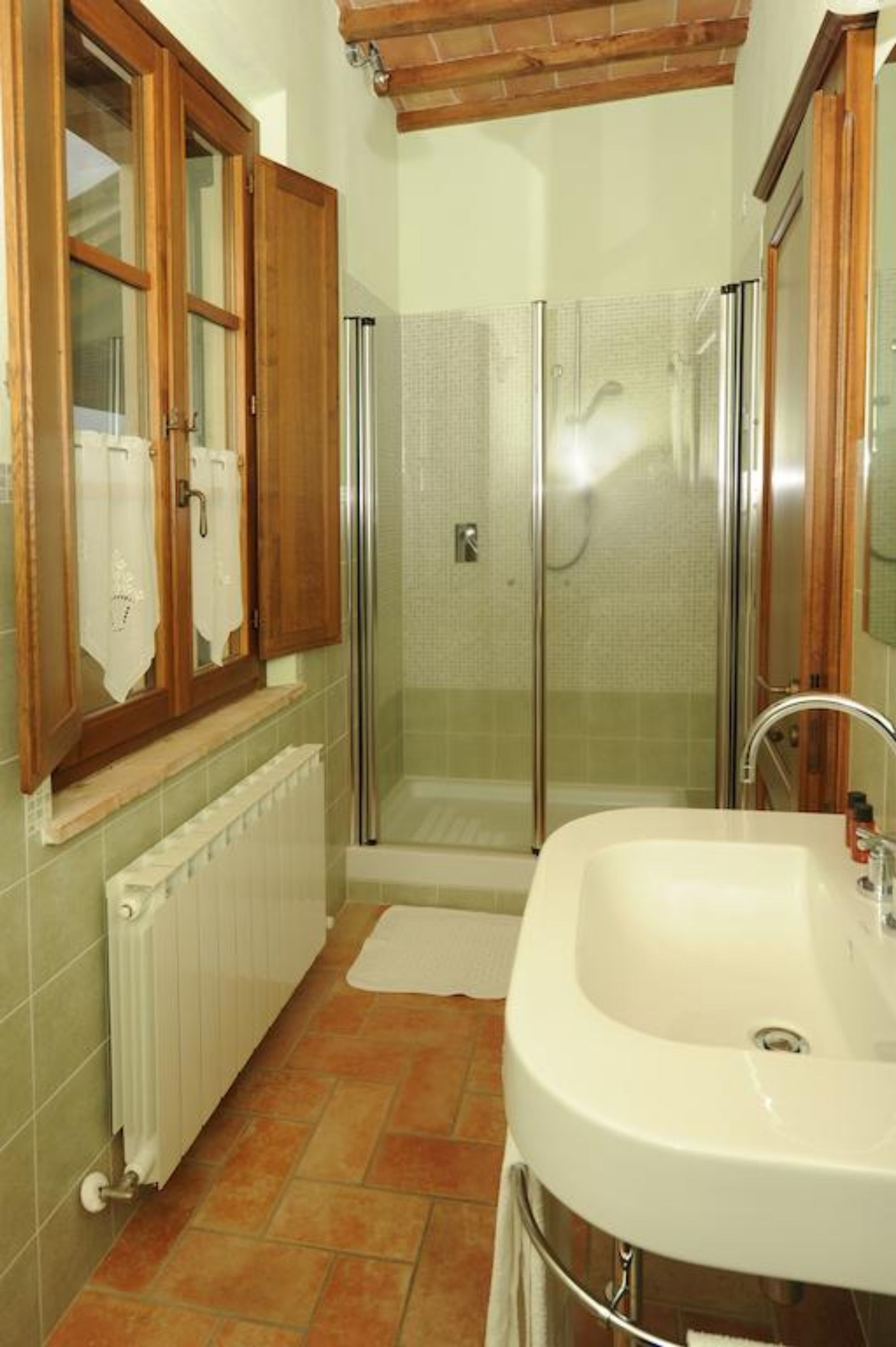 A bathroom with a glass-enclosed shower, a white sink, and wooden cabinets.