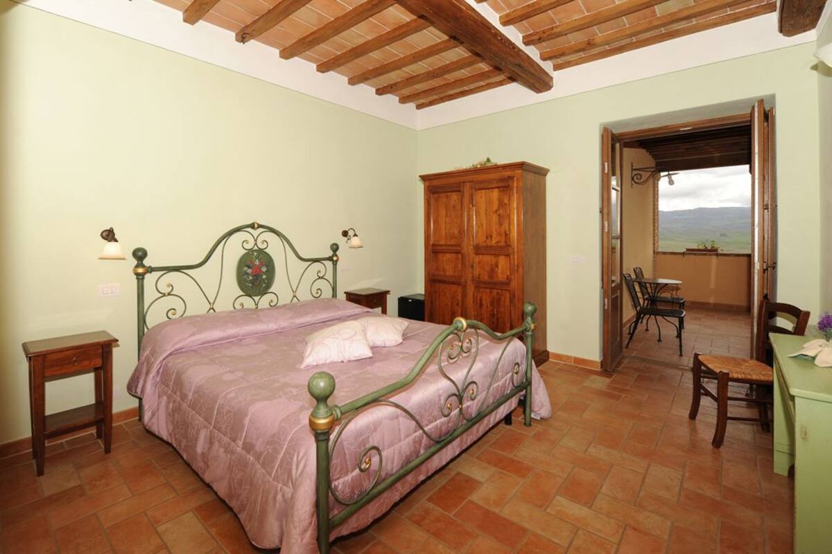 Un dormitorio con cama, armario de madera y vista a través de una puerta abierta.