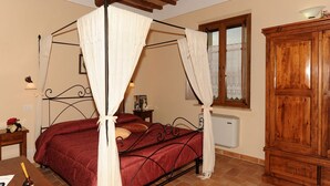 A bedroom with a four-poster bed, a wooden cabinet, and a window with lace curtains. - Agriturismo Poggio Tobruk (Pienza)
