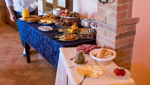 A breakfast buffet with various dishes and a person serving. - Agriturismo Poggio Tobruk (Pienza)