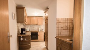 Una cocina compacta con armarios de madera, salpicadero de azulejos y horno empotrado.