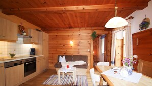 Un acogedor interior de cabaña de madera con cocina, comedor y sofá.