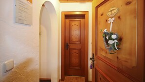Un pasillo con una puerta de madera, un letrero en la pared y un adorno navideño.
