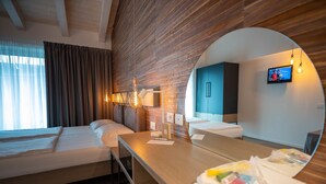 Una habitación de hotel con dos camas, techo de madera, televisor y espejo.