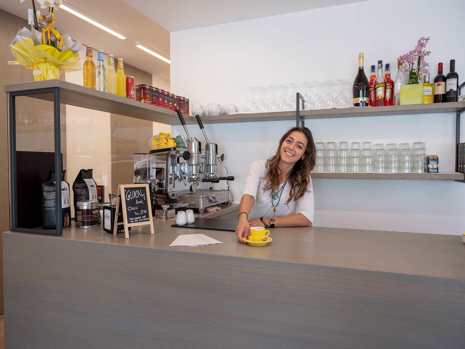 Een koffiebar toonbank met een koffieapparaat, een krijtbord en diverse dranken en toevoegingen.