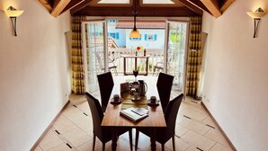 A dining area with a wooden table and chairs, a view of the outside, and a skylight above. - Vacation apartment Enzian in Haus Schmid - 90sqm - 1 - 3 persons (Grassau)