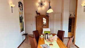 A dining area with a wooden table, brown chairs, a coffee pot, and a magazine. - Vacation apartment Enzian in Haus Schmid - 90sqm - 1 - 3 persons (Grassau)