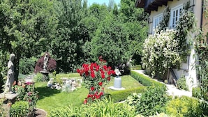 A garden with statues, a well-maintained lawn, and a building with a balcony. - Ferienwohnung Nr. 1 - "Panoramablick", 108 qm Obergeschoss, 1 separates Schlafzimmer (Bad Endorf)